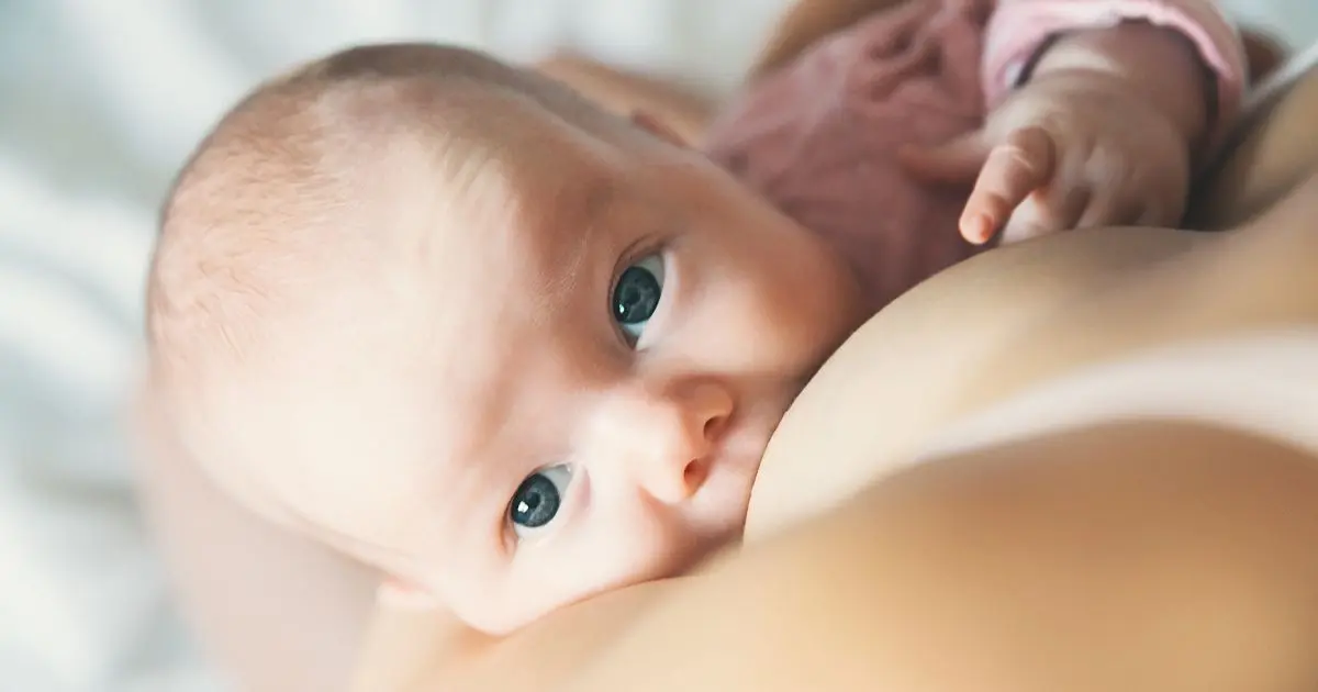 Breastfeeding newborn baby with bright eyes during feeding, capturing connection and comfort