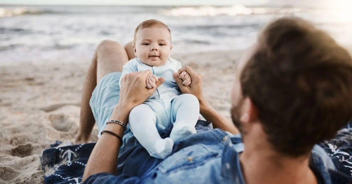 Father holding his baby on the beach while vacationing with a baby