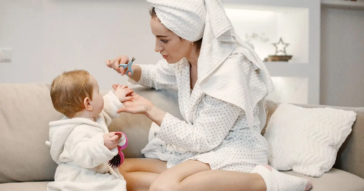 Mom trimming her baby’s nails after bath time as part of a careful daily baby care routine at home.