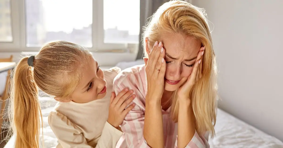 Mental load and mom burnout as an overwhelmed mother is comforted by her daughter, highlighting the emotional impact of invisible caregiving responsibilities.