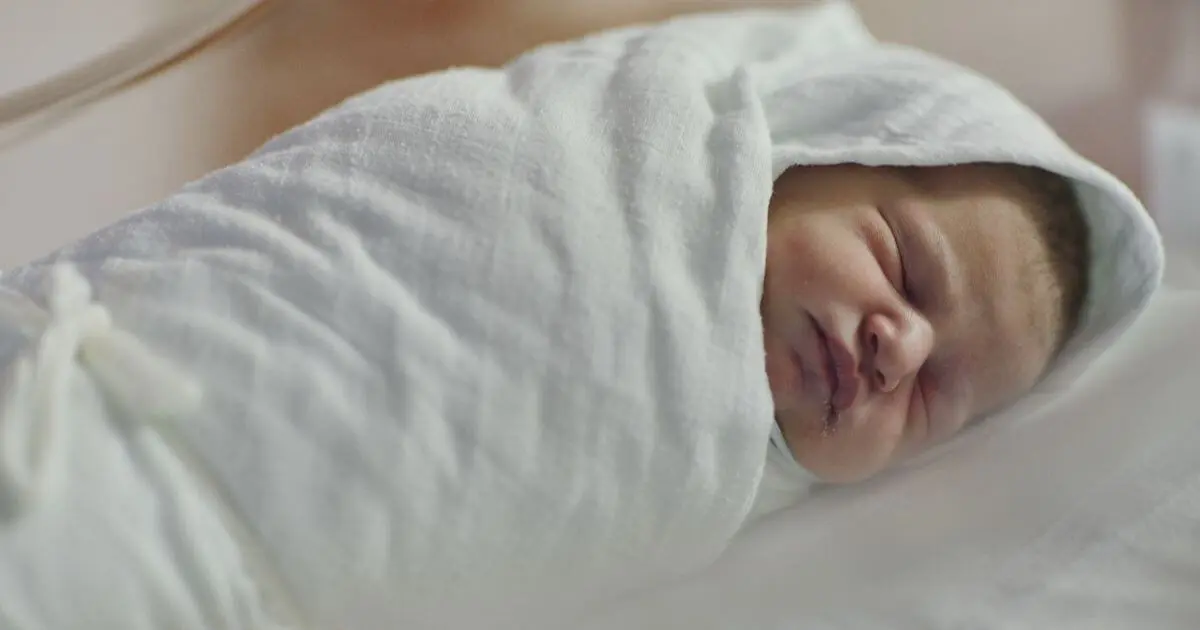 Newborn baby sleeping peacefully while swaddling in a soft white blanket, showing safe swaddling techniques that help babies sleep longer and feel secure.