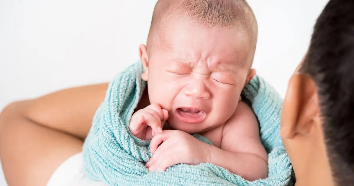 Soothing a baby: a newborn wrapped in a towel crying while a parent leans close, trying to calm and comfort them.