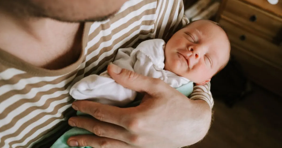 Baby Visitors moment with father holding sleeping newborn baby in arms