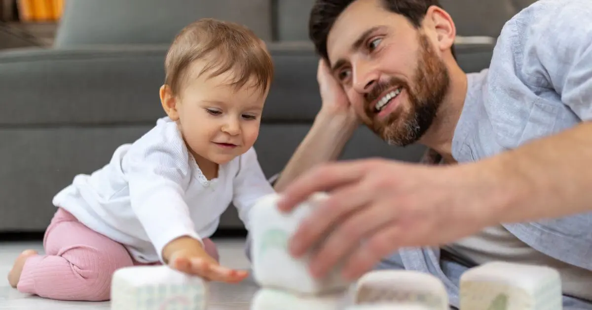 Father’s Day bonding activity with dad and toddler playing together on the floor at home