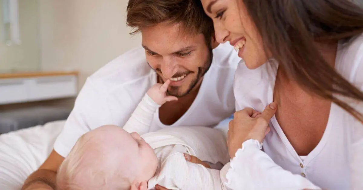 Happy mother and father relaxing on the bed with their newborn, sharing love and bonding moments that strengthen marriage after baby at home.