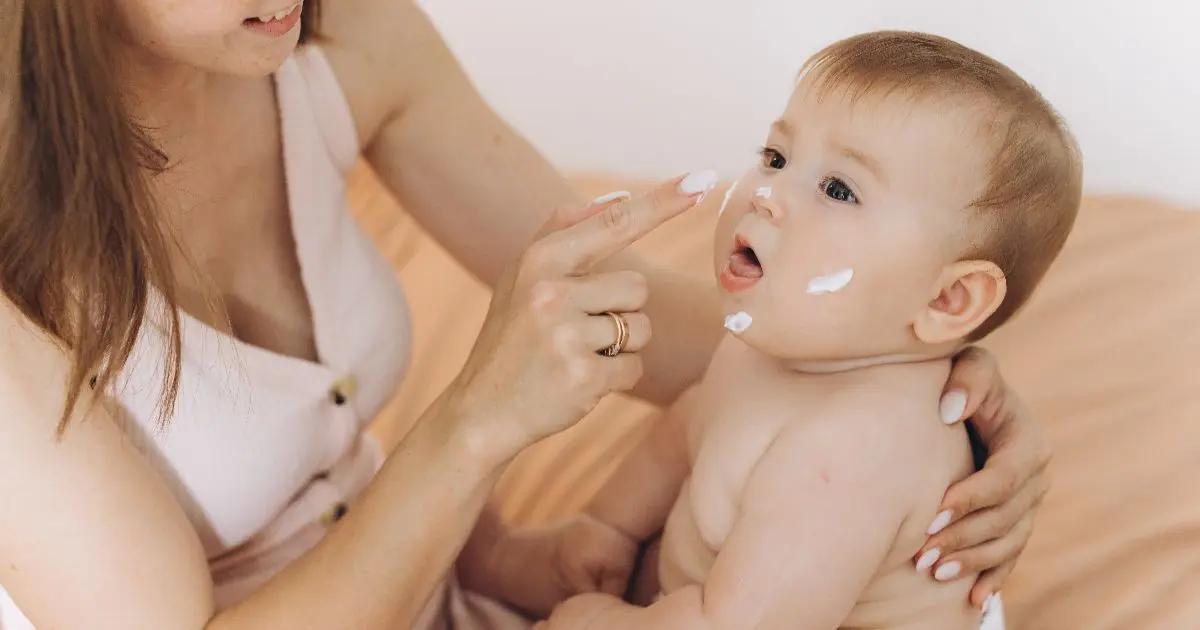 Mother applying moisturizer to her newborn baby’s face during a gentle baby care and skincare routine