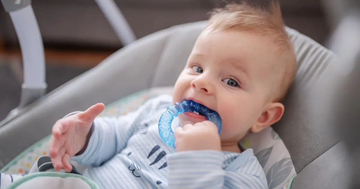 Baby teething baby boy biting a teether while lying in a rocker chair