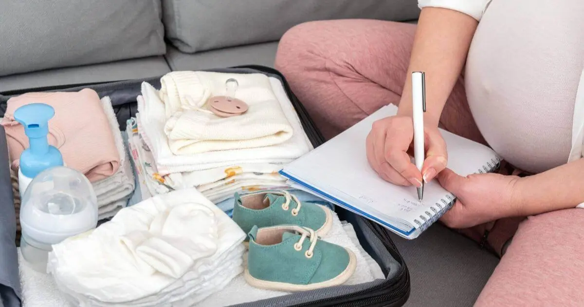Pregnant woman writing notes beside a packed suitcase and baby essentials, featuring a detailed Hospital Bag Checklist for moms preparing for childbirth and hospital stay.