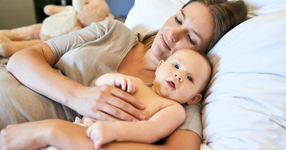 Postpartum Recovery featuring a mother resting with her baby in bed, illustrating the importance of healing, bonding, and self-care during the postpartum period.