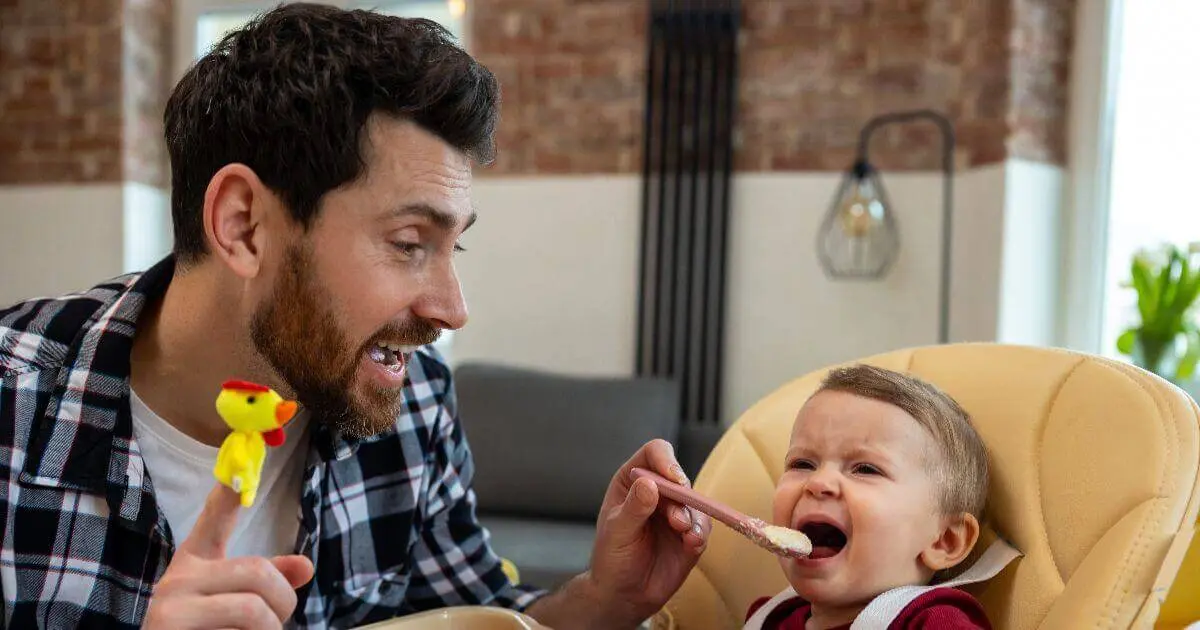 Introducing Solids Step by Step: What, When, and How to Feed Your Baby Father feeding his crying infant daughter during introducing solids at home in a modern interior.