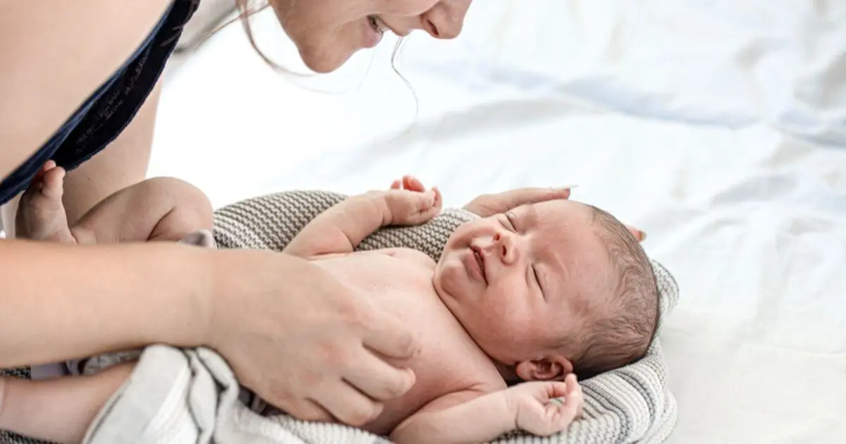 Mother interacting with her newborn baby during a diaper change, encouraging eye contact, communication, and social development. These early interactions support important Baby Growth Milestones in the first months.