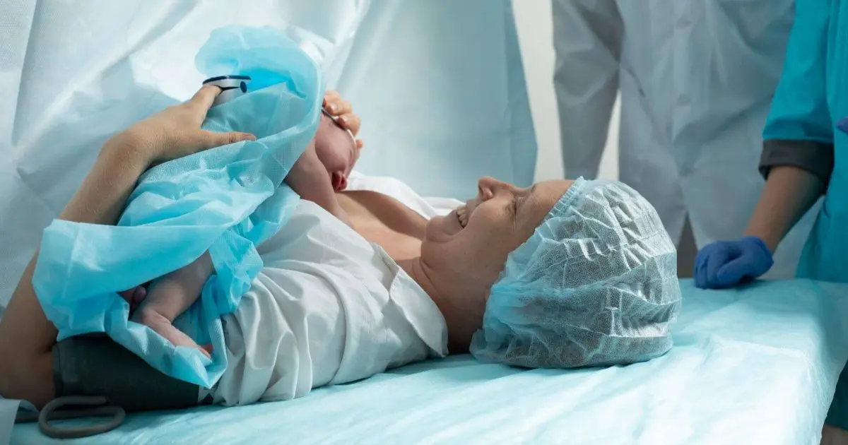 The Reality of C-Section Recovery – What No One Ever Told You c-section recovery moment as a mother holds her newborn baby in a hospital room, supporting early bonding and emotional healing after birth