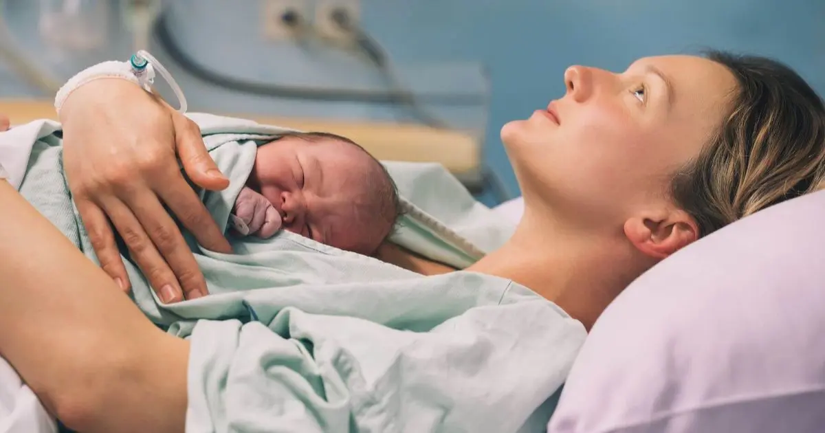 Mother hugging her newborn baby in a maternity hospital after delivery, representing birth trauma and emotional healing after an unexpected birth experience.