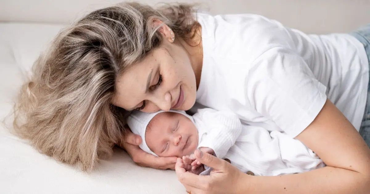 Matrescence: New mother gently cuddling her sleeping newborn in bed, illustrating the quiet moments of bonding and the emotional journey of matrescence.
