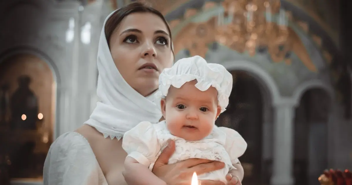 Mother holding baby during Baptism ceremony in church, soft emotional moment with candlelight
