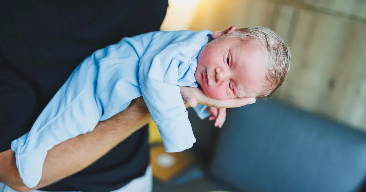 Soothing a baby: a father holding a newborn in his arms, gently supporting and calming the baby in a peaceful moment.