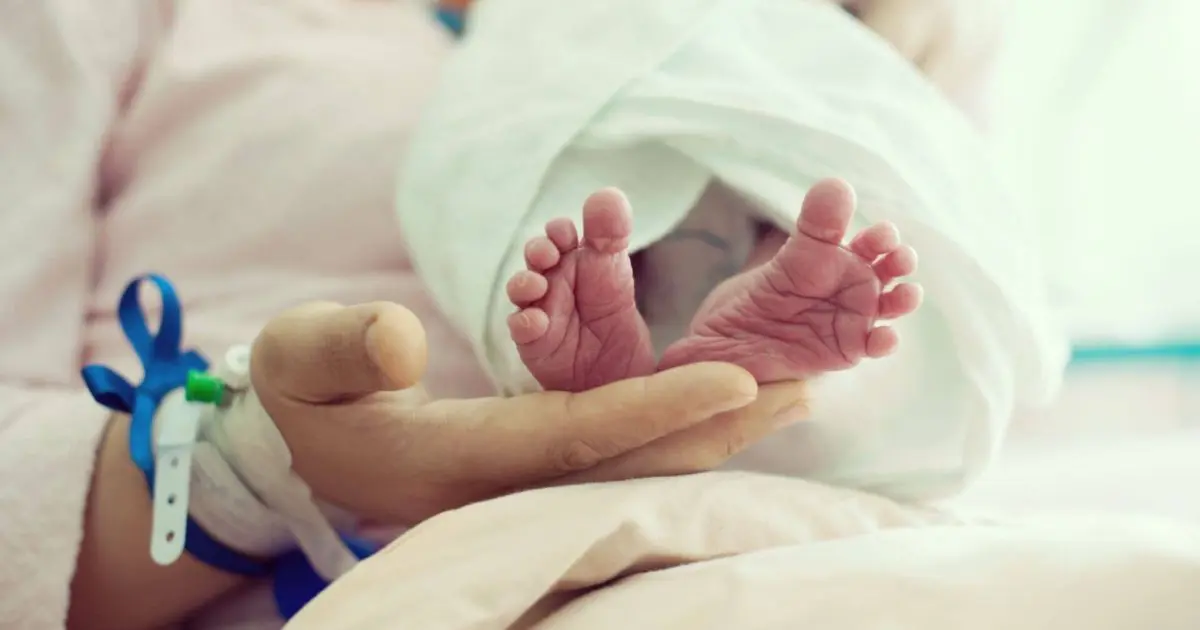 Newborn baby with hospital ID bracelet, representing birth trauma and early moments after delivery.