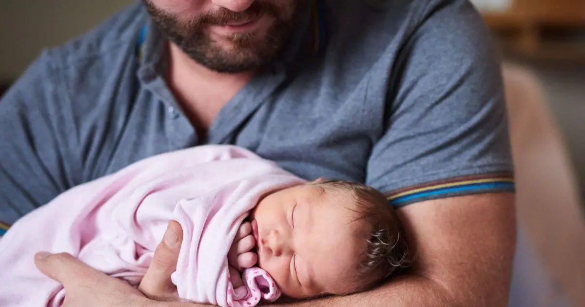 Sleeping newborn baby wrapped in a soft pink blanket while resting safely in her father's arms. This heartwarming moment highlights early bonding and emotional connection, an important part of Baby Growth Milestones during the first weeks of life.