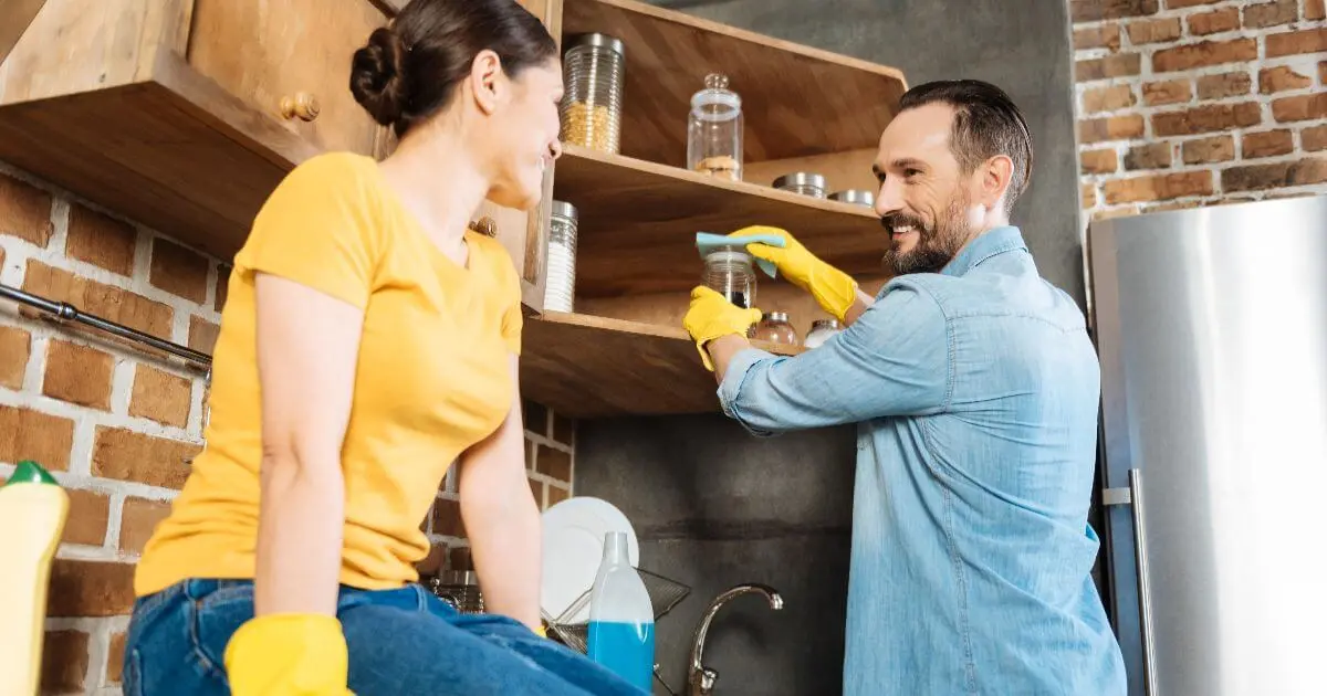 Mental load shared between partners as a couple cleans the kitchen together, showing equal household responsibilities and reducing the invisible mental load of family life.