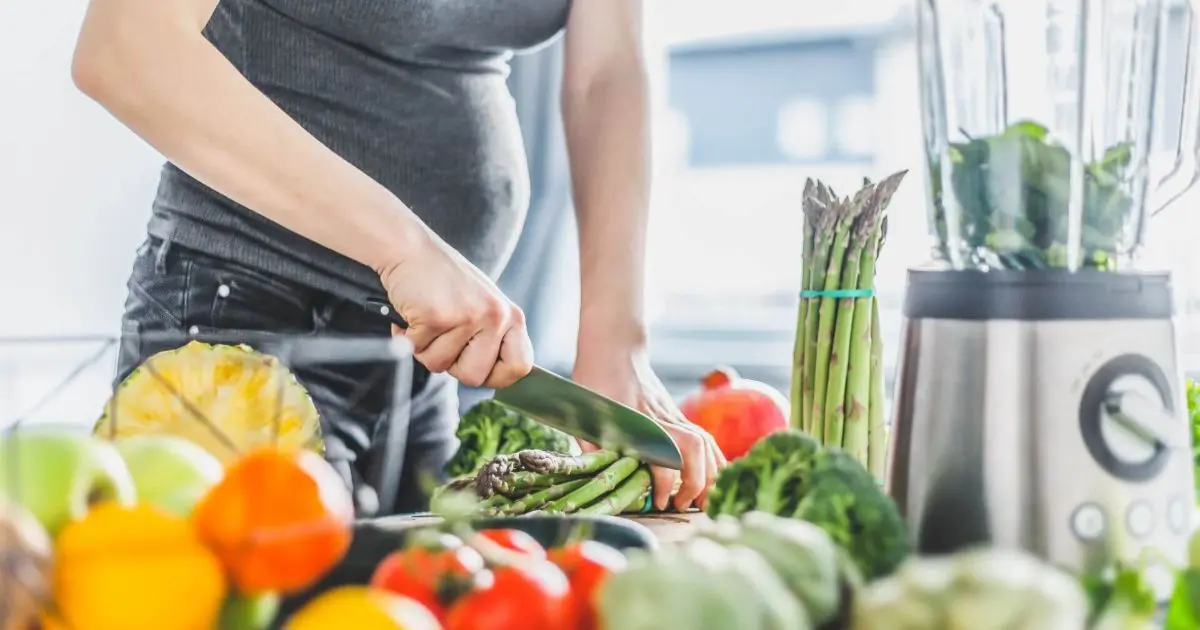 Pregnant woman cooking healthy, nutritious meals as part of a balanced pregnancy nutrition diet