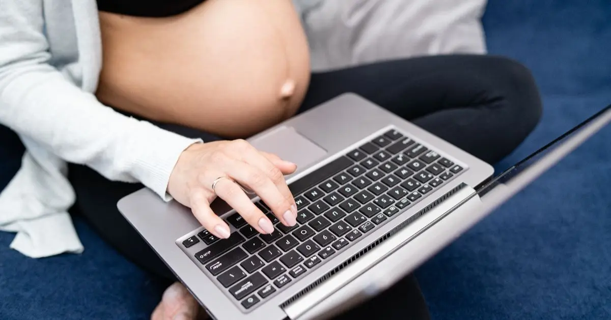 Data-Driven Pregnancy – The Algorithm That Might Predict Labor Pregnant woman using a laptop while tracking health data during a data-driven pregnancy, wearing a smart ring and monitoring pregnancy information online.