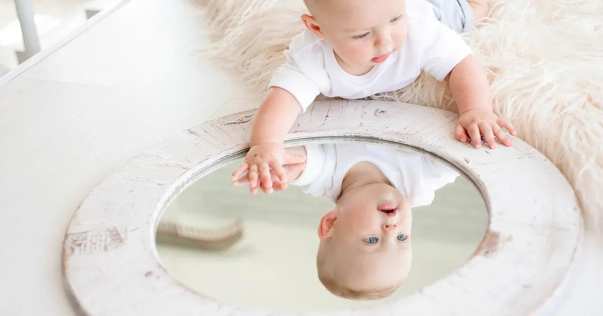 What to Watch for During Summer? Sensory Activities Toddlers and Babies Love (0–12 Months) Baby exploring their reflection in a mirror during sensory play activity, supporting early learning and development through sensory activities toddlers and babies enjoy during the first year.