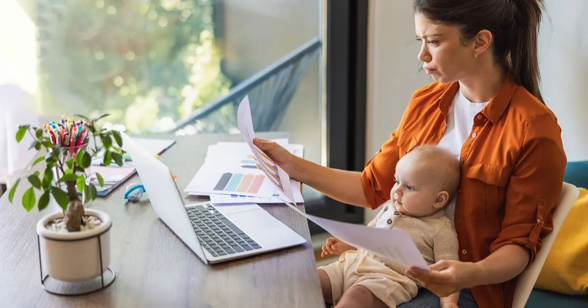 Returning to Work: Stressed mom balancing paperwork, a laptop, and baby care while adjusting to returning to work.