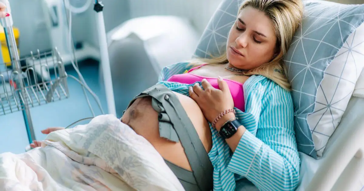 The Stages of Labor: What Really Happens During Labor and Birth? Stages of Labor visual showing a pregnant woman in early labor resting in a hospital bed while contractions and baby's heartbeat are monitored.
