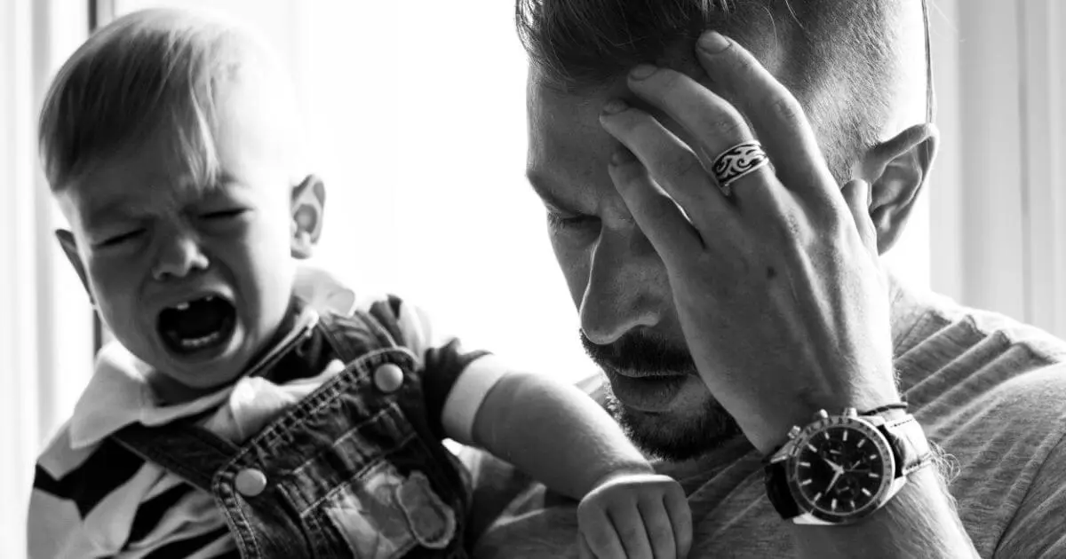 stressed father holding crying baby, exhaustion and pressure affecting relationship after baby