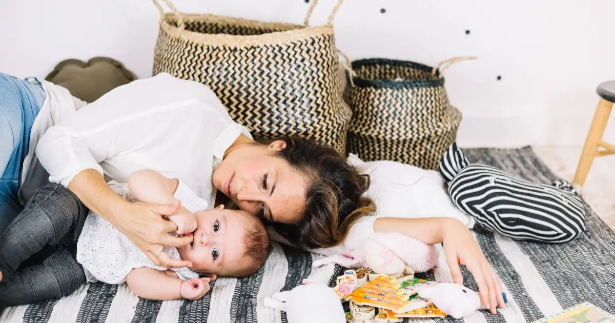 Mom Burnout in Summer: Exhausted mother caring for her baby at home while managing the emotional and mental load of summer motherhood.