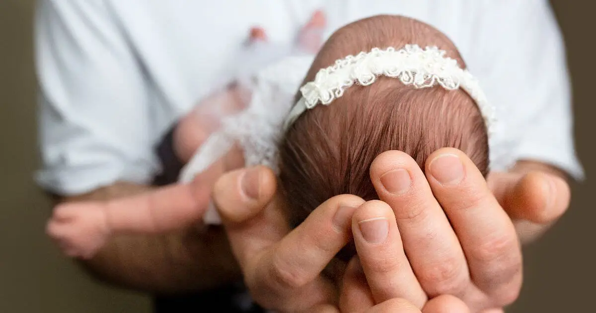 Newborn baby held safely in loving hands after Baptism ceremony, soft emotional moment