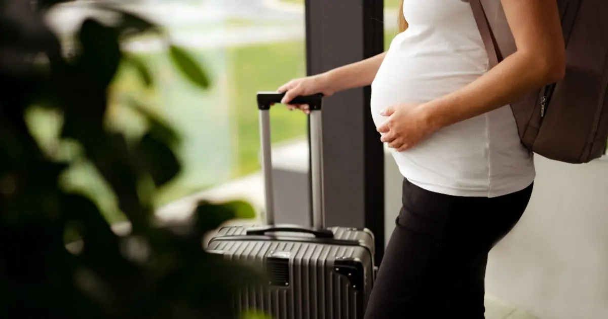 Pregnancy myths – pregnant woman traveling with suitcase at airport during pregnancy journey