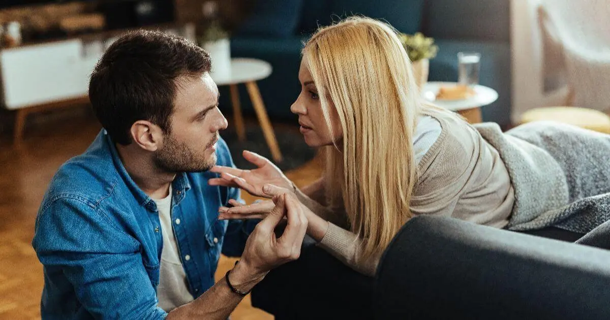 A young couple sitting at home having a serious conversation about their relationship, reflecting the emotional challenges of marriage after baby.